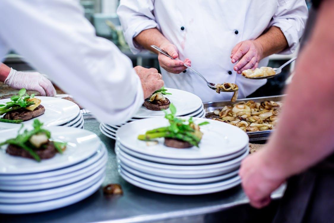 Chefs in a busy restaurant kitchen finalizing dishes on plates before service