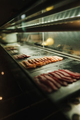 Assorted cuts of fresh meat neatly stored in a restaurant refrigerator for kitchen prep and menu essentials